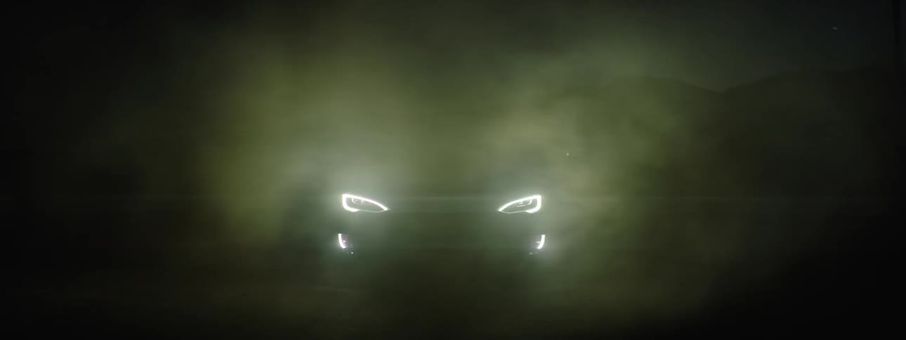 Parked car turns on headlights on foggy night