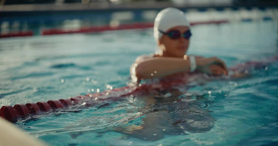 Close up of a young woman swimming in an outdoor pool during daytime
