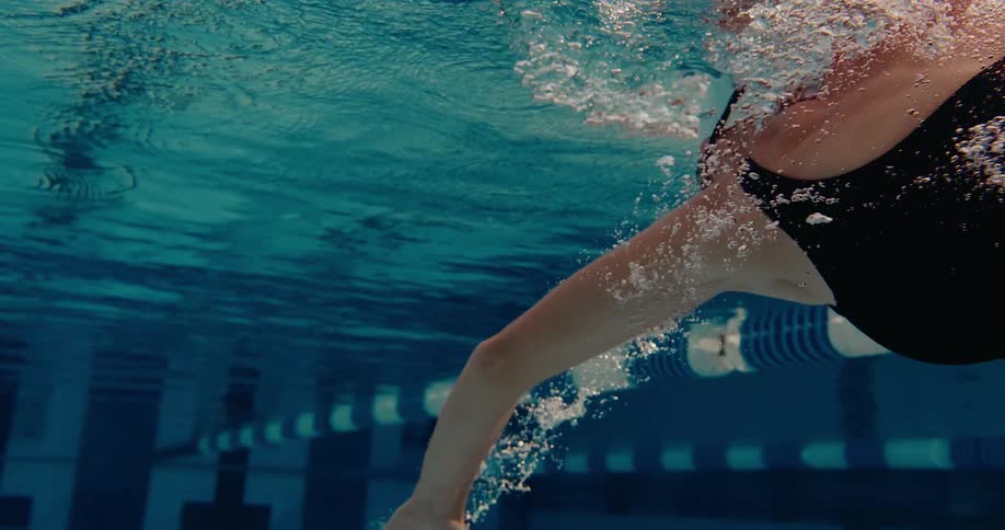 Woman swimming above blue and white lane with visible bubbles in underwater pool view