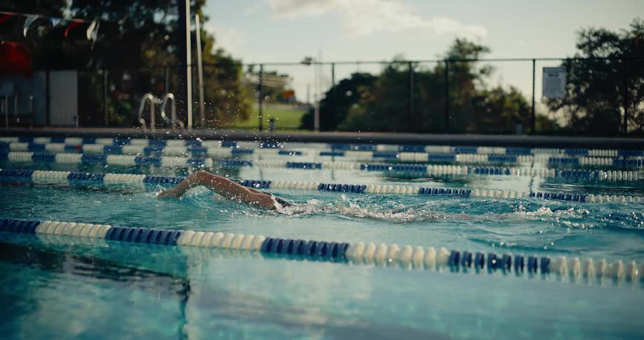 Swimmer performing freestyle in an outdoor olympic pool lane