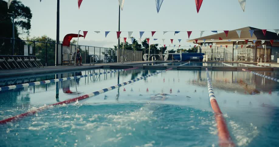 Woman stands at the edge of the swimming pool and dives into the water