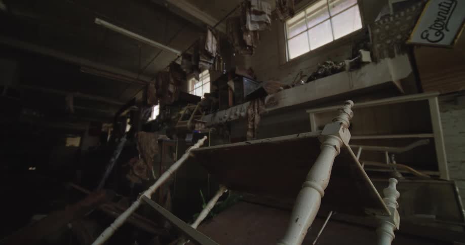 Broken white frame rests among damaged furniture in abandoned setting