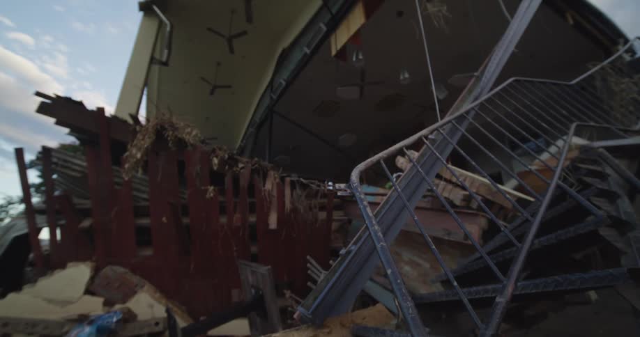 Twisted metal staircase and scattered debris in interior damaged by structural collapse