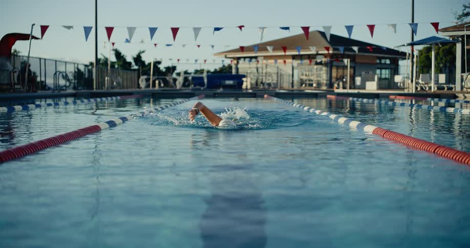 A person practices swimming in the pool at midday
