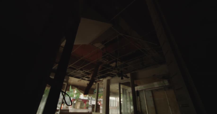 Building interior structure with damaged ceiling exposed wiring and exterior area visible in the background