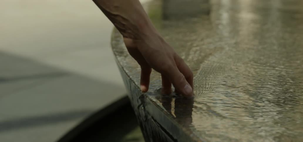 A man traces his hand in fountain water
