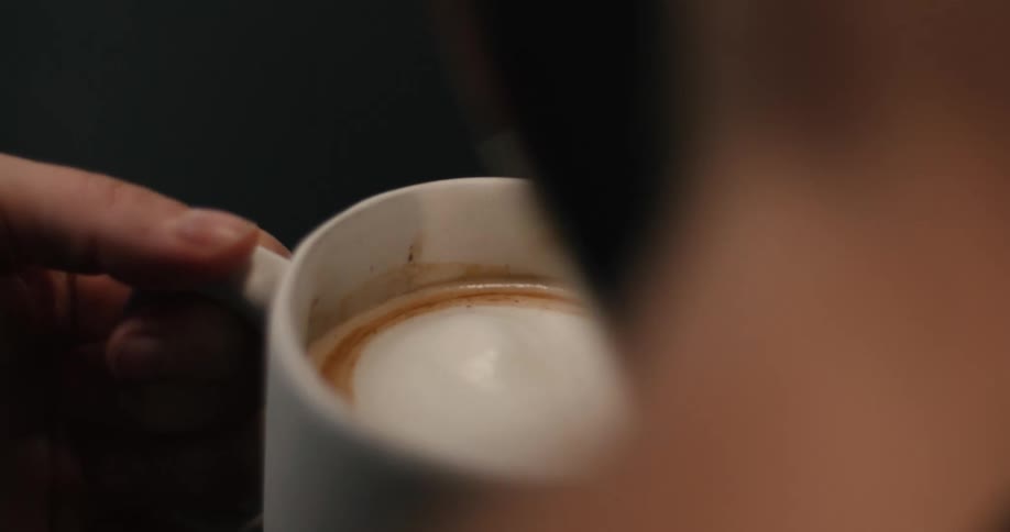 The person fills the cup with coffee and cream