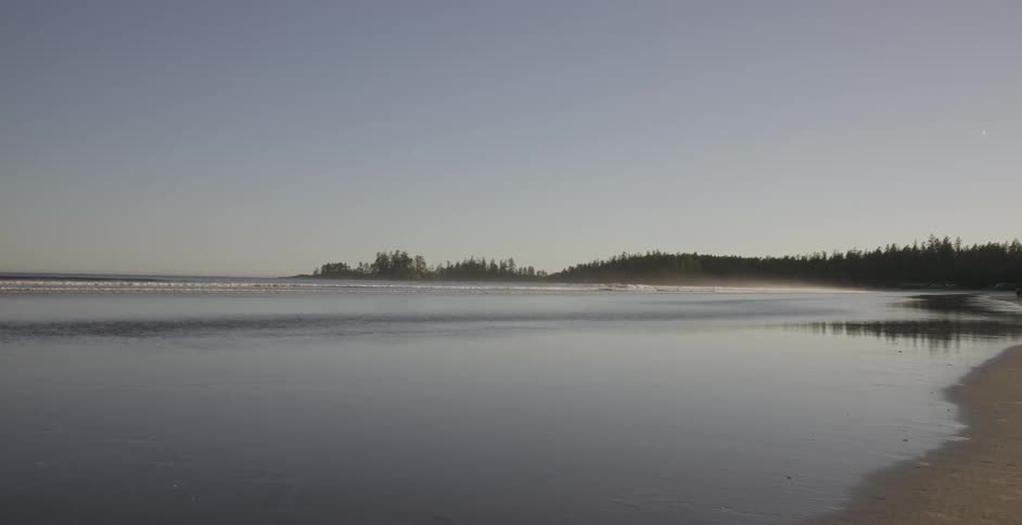 Ocean waves flowing up onto beach on clear day