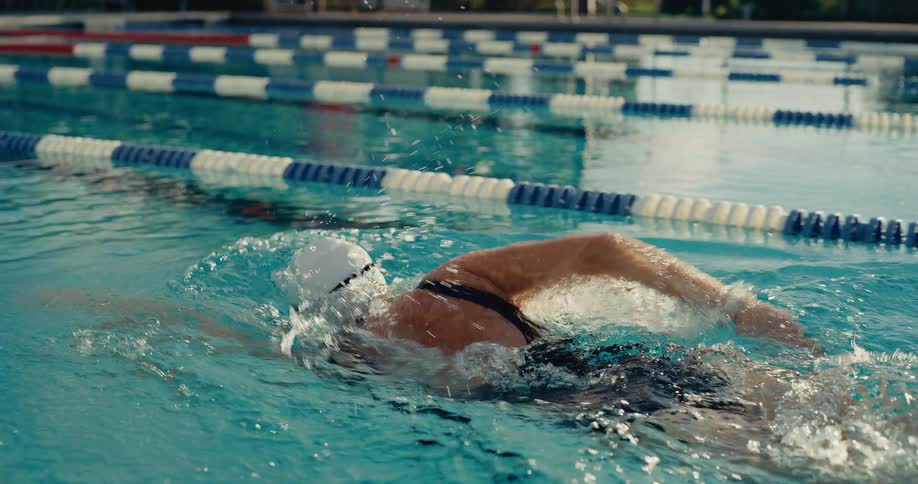 Water splashes as a woman swims across the pool