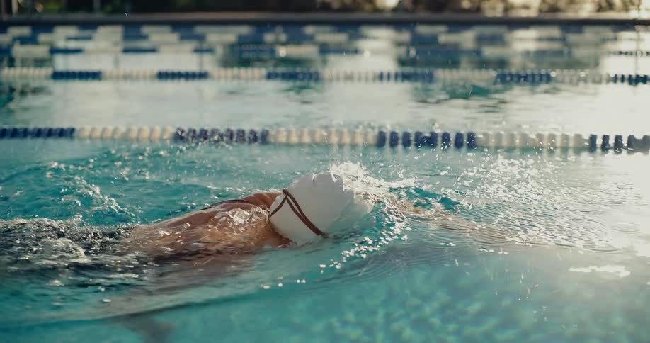 Water splashes as a woman swims across the pool
