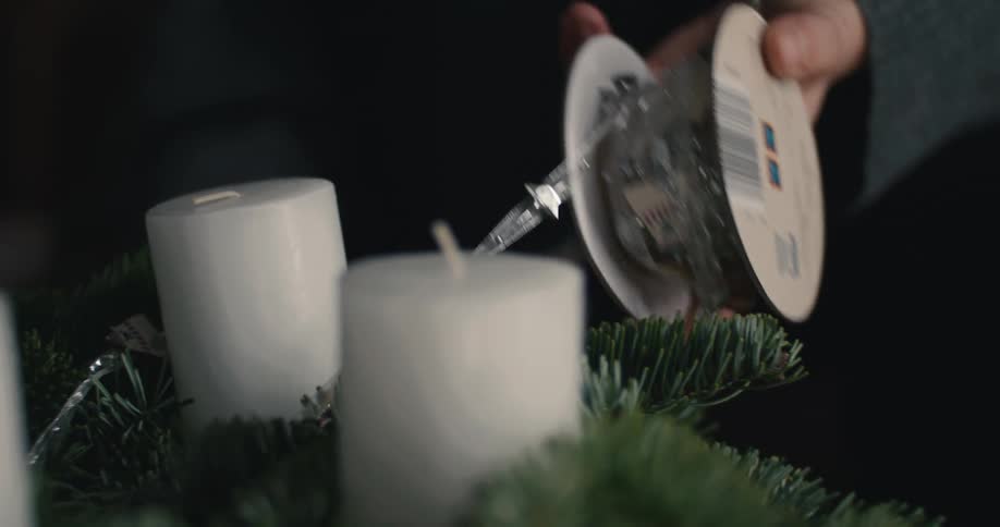 A person decorating a wreath with candles