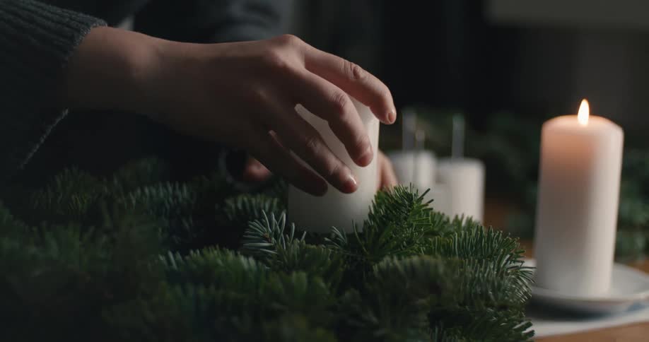 The woman is putting a candle in the wreath