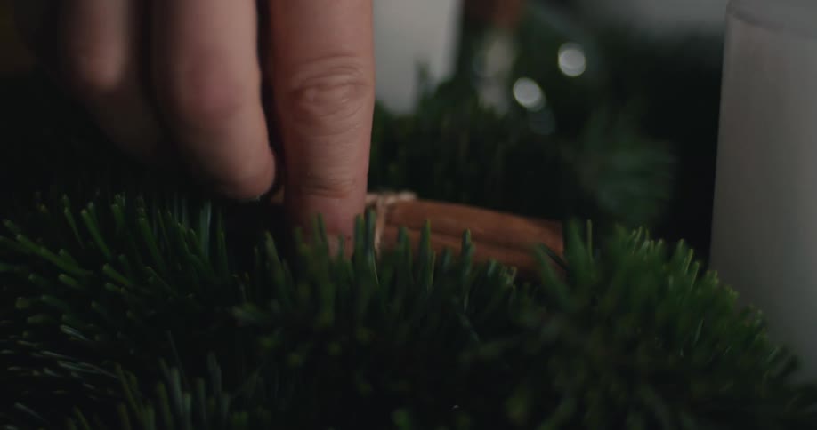 A person putting cinnamon sticks on a wreath