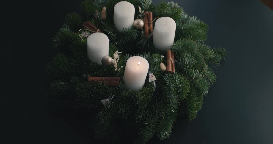 A person lighting a candle on a wreath