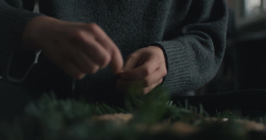 The woman is sewing a wreath