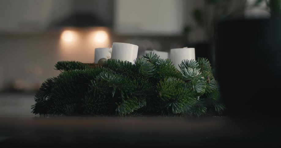 The woman places a wreath with candles on the table