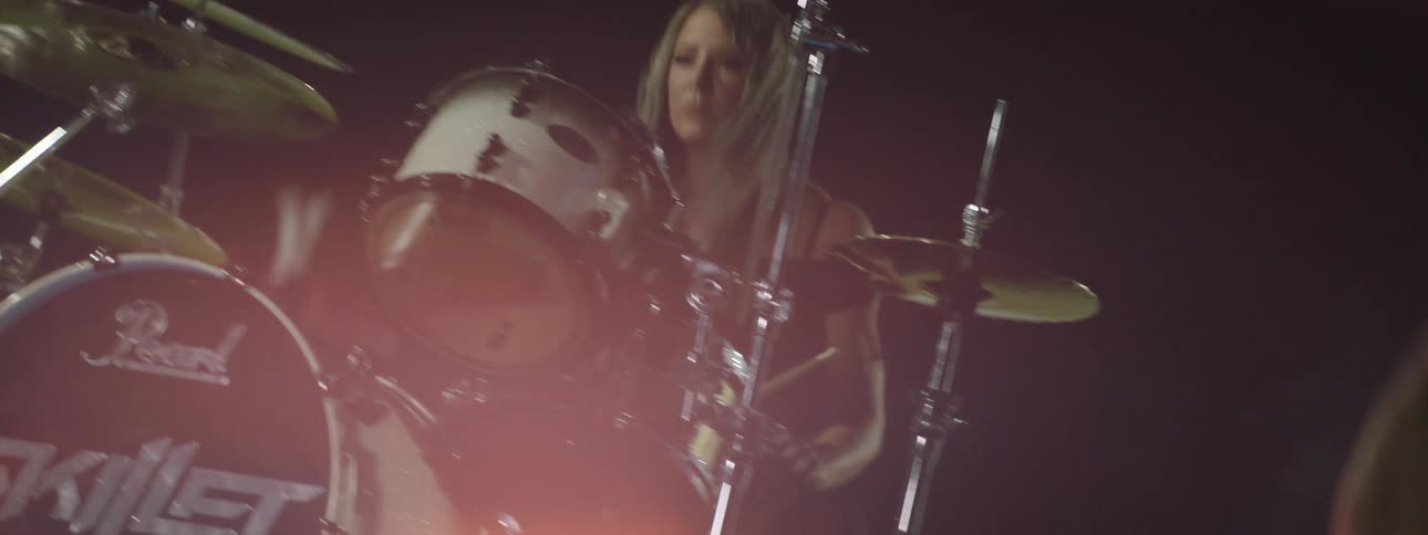 A young man plays a guitar at night during a concert accompanied by a woman performing with the band
