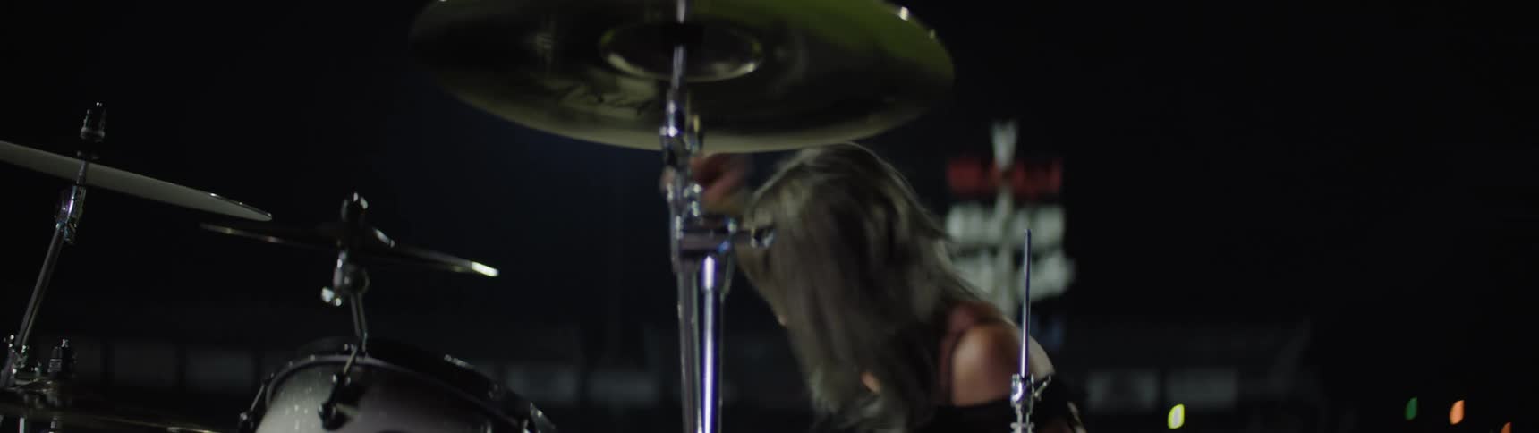Woman holds her drumsticks and swings her arms as she plays the drums