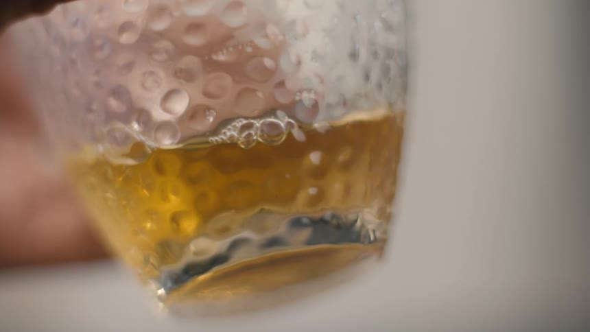 Person lifts a textured glass holding amber liquid