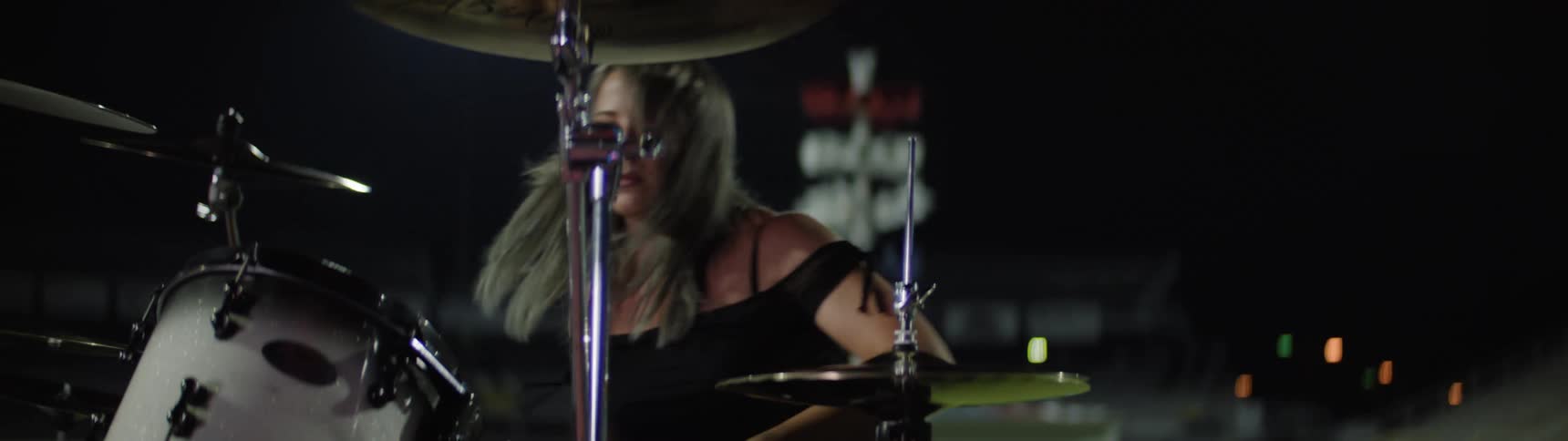 Woman holds her drumsticks as she plays the drums