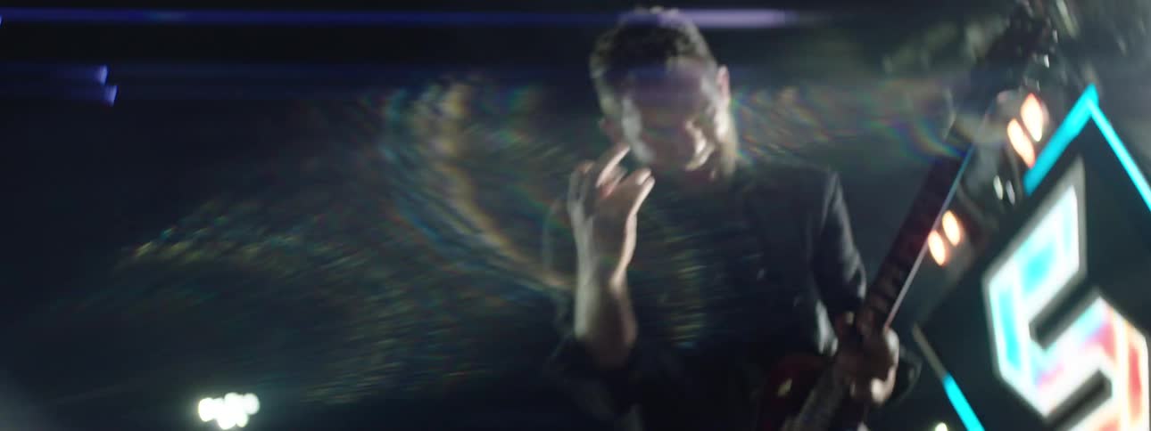 A young man excitedly plays the guitar during a concert at night