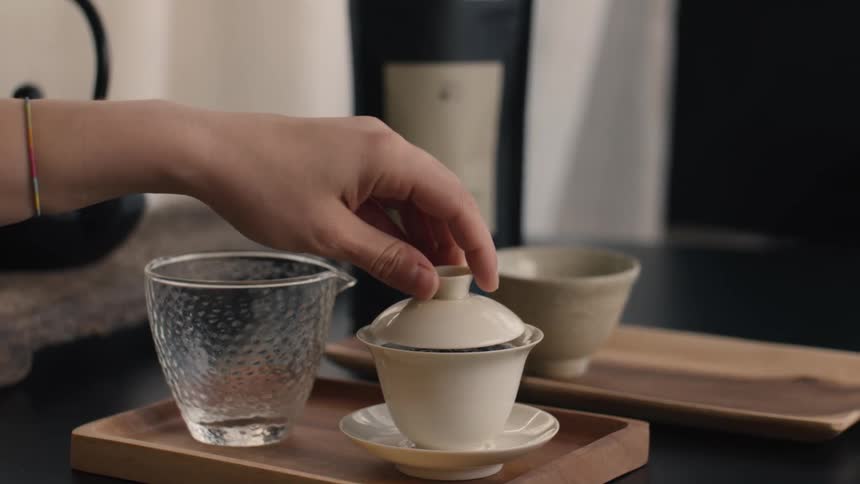 A womans arm prepares tea in a teacup at midday
