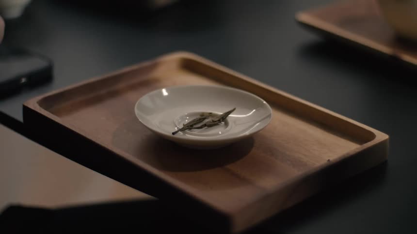 The white plate is sitting in the middle of a brown wooded try on the edge of the black table