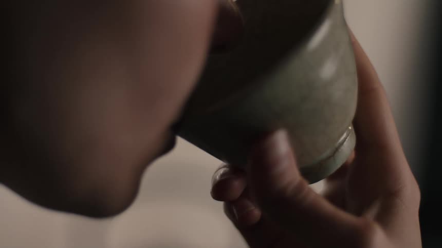 Person brings crackledglaze ceramic cup to mouth in act of beverage consumption