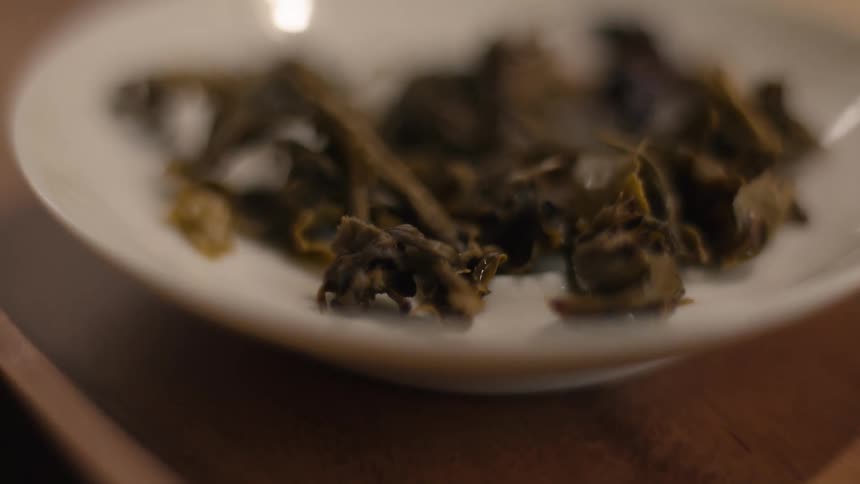 The green leaves are on the white plate that is sitting on the wooden tray