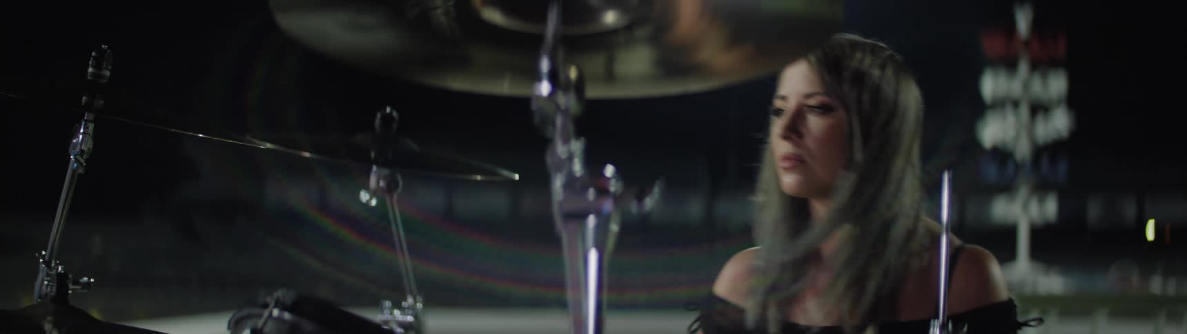 Woman holds her drumsticks as she plays the drums