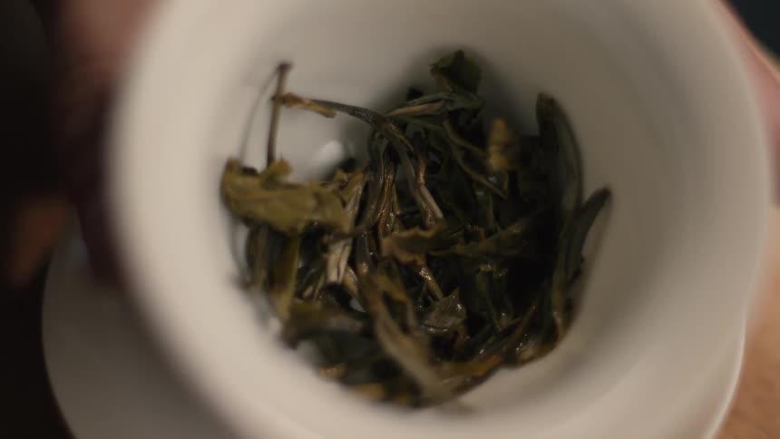 The person holds up a cup full of tea leaves