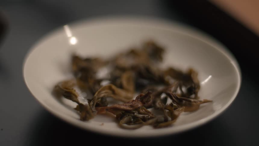 Dried mushrooms rest in white dish on dark surface