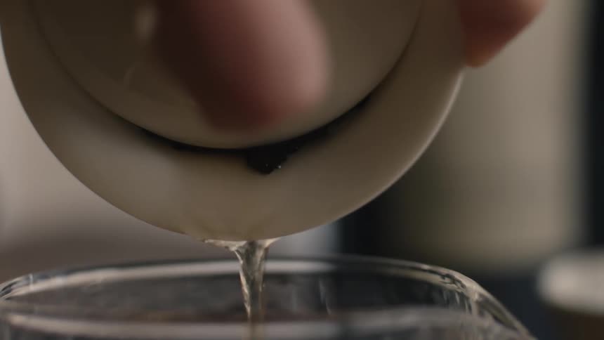 A person pours tea from a teacup into a jug