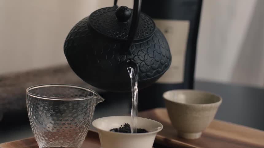 A kettle pouring water into a teacup