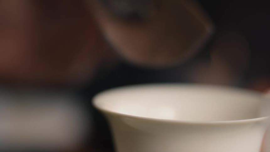 Close up of a person adding tea leaves to a teacup on table during daytime