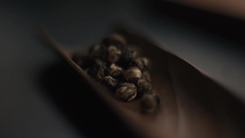 Whole black peppercorns are placed inside a wooden log indoors