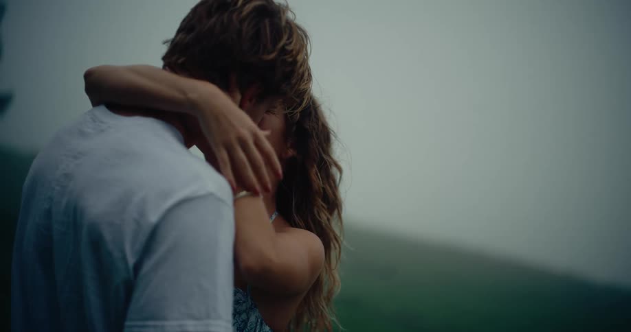 Couple kissing outdoors with flowers raised above their shoulders