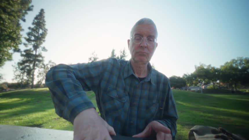 Elderly person in a blue plaid shirt opening an ipad