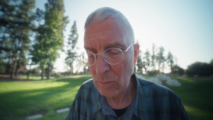 Man in blue plaid shirt types on tablet with keyboard on outdoor sunlit table