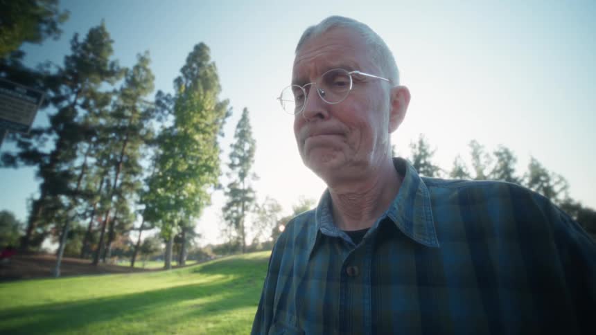 Person wearing a blue plaid shirt opening a tablet with a keyboard on an outdoor table in a wooded park