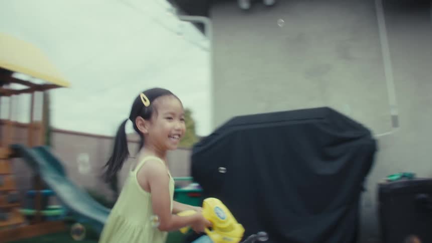 The girl chases her dad shooting bubbles at him