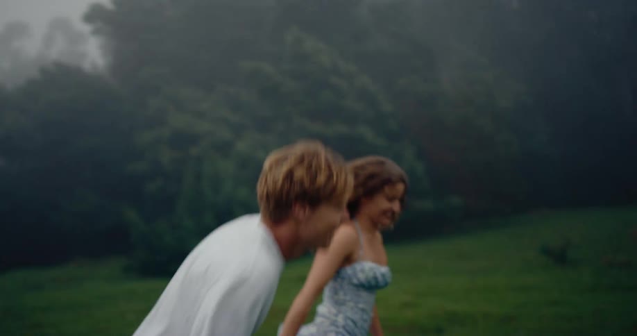 Couple running hand in hand in a grassy outdoor area