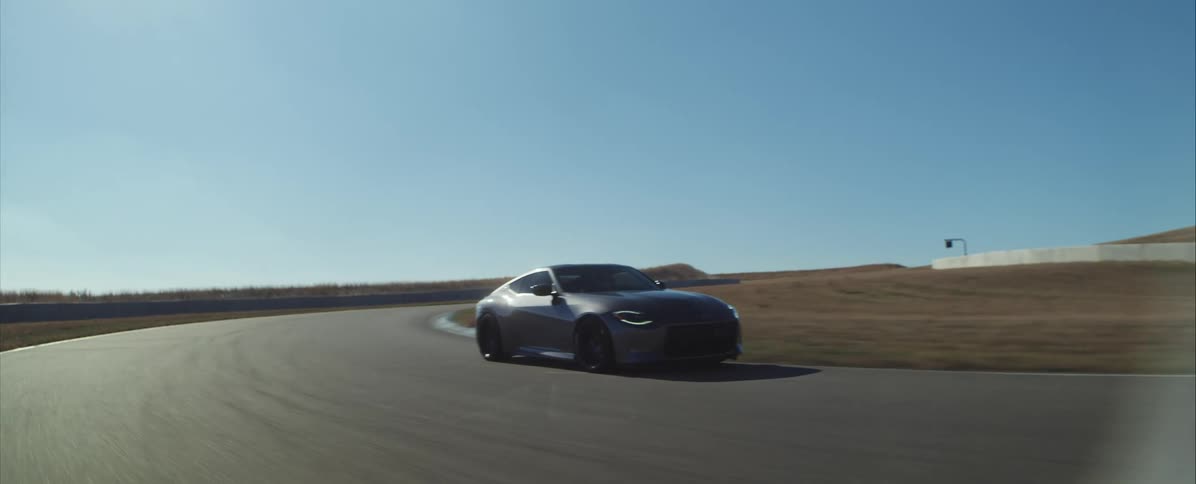 Sports car driving through a curve on a paved track under an open sky