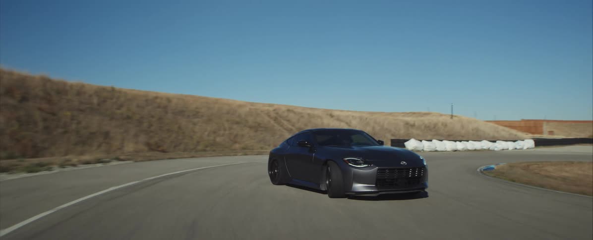 Black sports car cornering on racetrack with visible tire marks on the asphalt