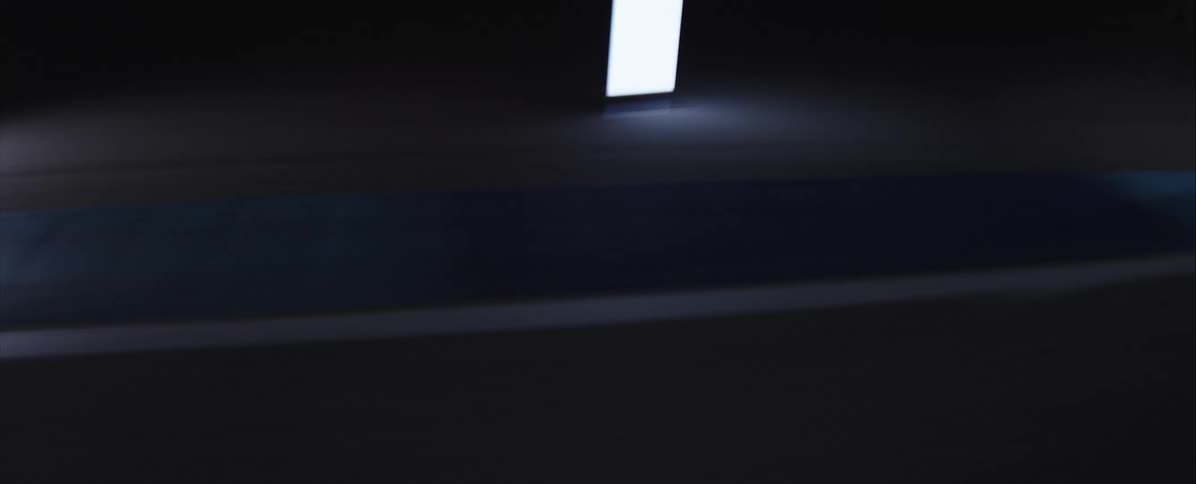 A lowangle shot races down the center of a striped road at high speed with glowing lights flashing by in the darkness