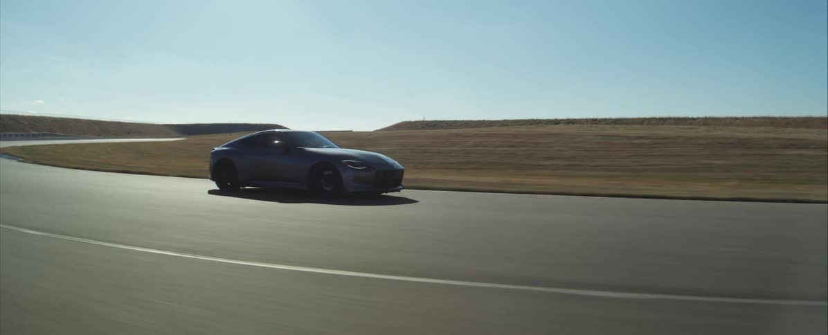 A black sports car driving on a large empty asphalt track