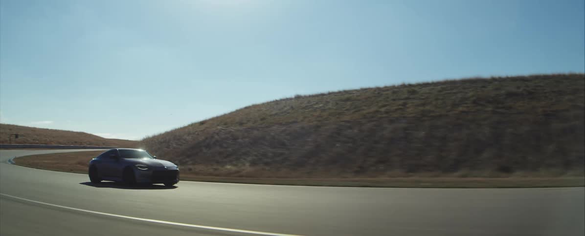 Sports car driving on a road surrounded by grassy slopes outdoors during day time