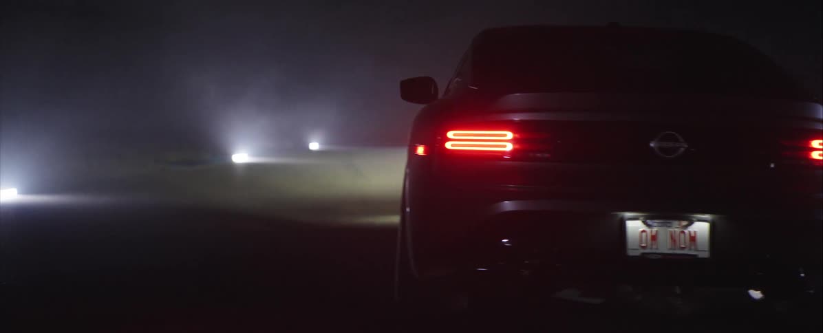 Dark nissan sports car driving at night with tail lights on and ohio license plate