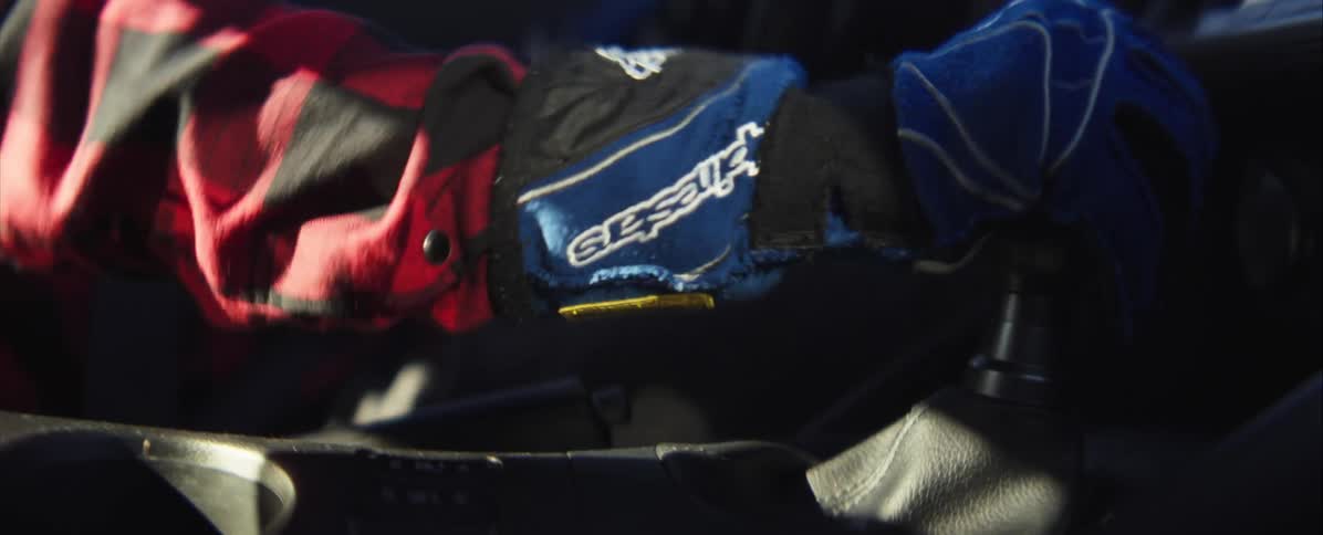 A gloved hand is shifting a gear shift in a vehicle