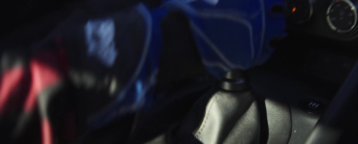 A close view of a car interior shows a gloved hand in a blue uniform reaching forward to quickly engage the gear shift knob